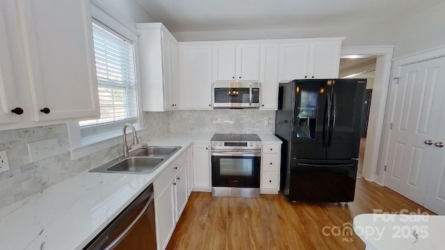 kitchen featuring a sink, stainless steel appliances, light wood finished floors, and white cabinetry