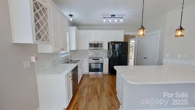 kitchen featuring appliances with stainless steel finishes, light wood-style flooring, white cabinetry, decorative backsplash, and a wealth of natural light