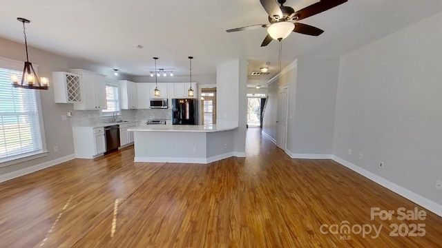 kitchen featuring tasteful backsplash, light countertops, baseboards, black appliances, and white cabinetry