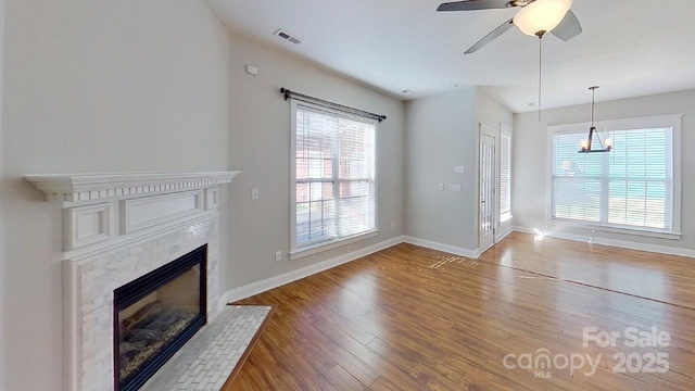unfurnished living room featuring plenty of natural light, a premium fireplace, wood finished floors, and visible vents