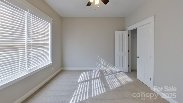 carpeted spare room featuring a ceiling fan and baseboards