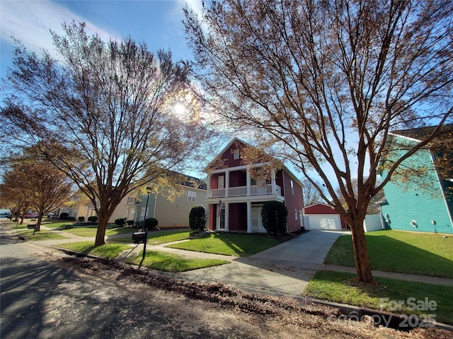 traditional home featuring concrete driveway, a balcony, a front yard, and a detached garage