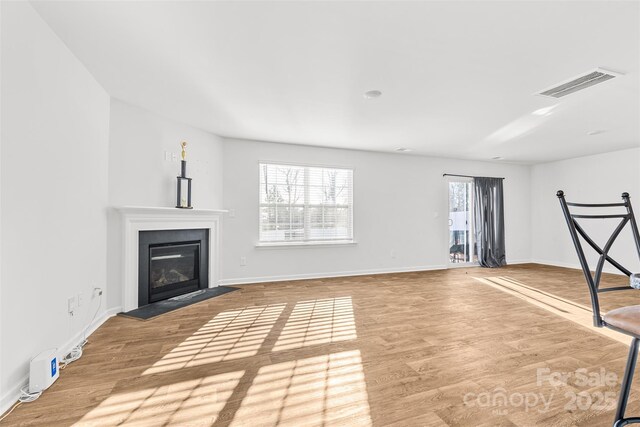 2120 Redstone Dr, York, SC 29745 - unfurnished living room featuring a glass covered fireplace, wood finished floors, and baseboards