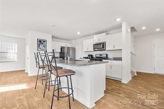 2120 Redstone Dr, York, SC 29745 - kitchen with stainless steel appliances, a kitchen breakfast bar, light wood-type flooring, white cabinetry, and recessed lighting