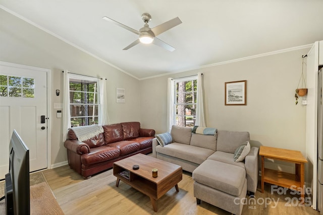 living room with lofted ceiling, ornamental molding, light wood-style floors, baseboards, and ceiling fan