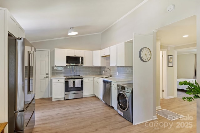 kitchen featuring a sink, appliances with stainless steel finishes, ornamental molding, and washer / clothes dryer