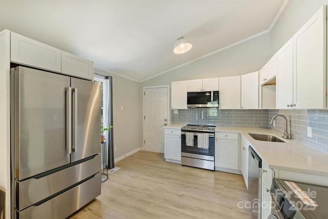 kitchen with stainless steel appliances, a sink, backsplash, lofted ceiling, and light countertops