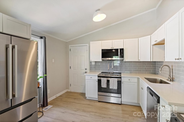 kitchen with lofted ceiling, backsplash, visible vents, a sink, and appliances with stainless steel finishes