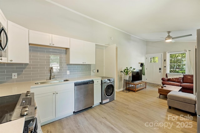 kitchen with white cabinets, a sink, a ceiling fan, appliances with stainless steel finishes, and washer / dryer