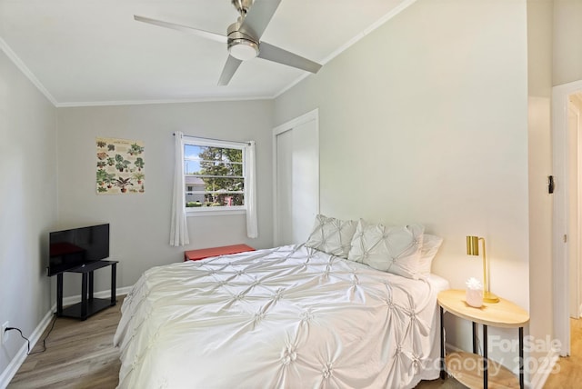bedroom with lofted ceiling, a ceiling fan, wood finished floors, a closet, and ornamental molding