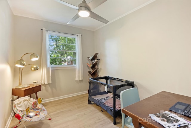 exercise room featuring light wood-style flooring, a ceiling fan, baseboards, and ornamental molding