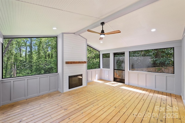 unfurnished sunroom featuring ceiling fan, a large fireplace, and beamed ceiling