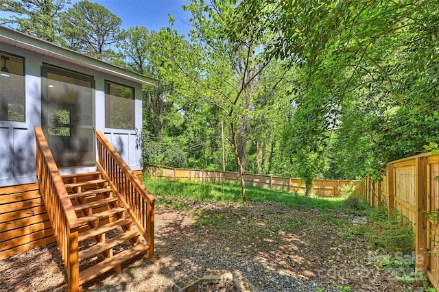 view of yard featuring a sunroom, a fenced backyard, and stairway