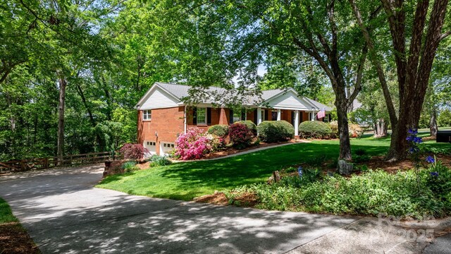 ranch-style home with a garage, driveway, a front yard, and brick siding
