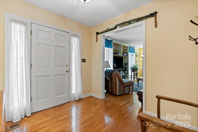 foyer featuring baseboards, visible vents, and light wood-style flooring