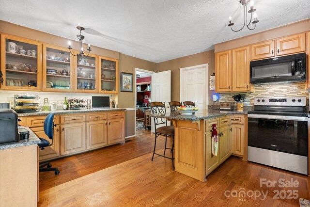 kitchen with light wood finished floors, black microwave, a peninsula, a kitchen bar, and stainless steel electric range oven