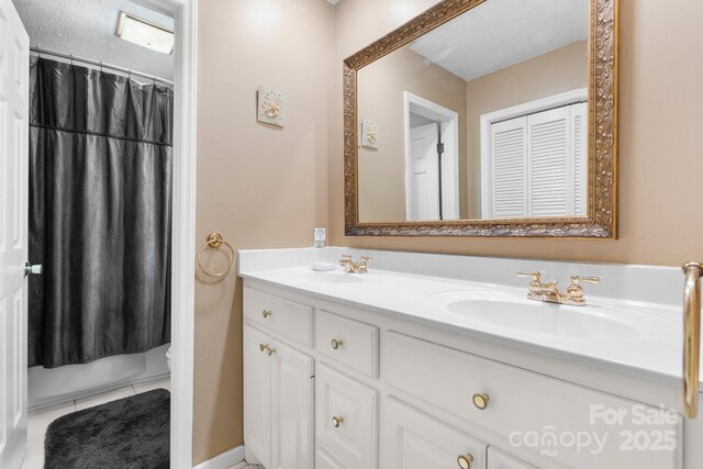 full bathroom featuring a sink, a textured ceiling, double vanity, toilet, and tile patterned flooring