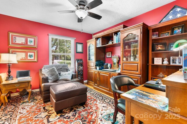 office area featuring baseboards, a ceiling fan, wood finished floors, and a textured ceiling