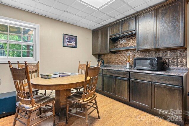 dining area featuring a drop ceiling and light wood-style flooring