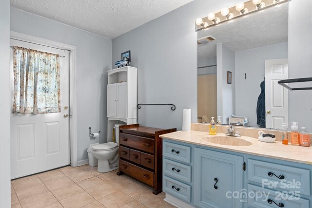 bathroom featuring tile patterned floors, a textured ceiling, toilet, visible vents, and vanity