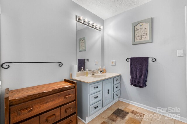 bathroom featuring tile patterned floors, baseboards, vanity, and a textured ceiling