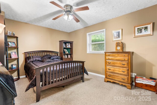 carpeted bedroom featuring baseboards, a textured ceiling, and ceiling fan