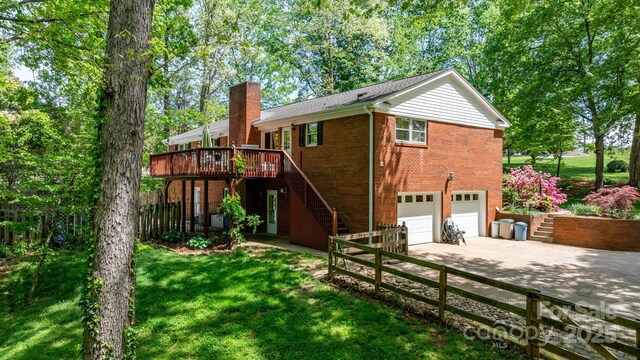 exterior space featuring an attached garage, a chimney, brick siding, and stairs
