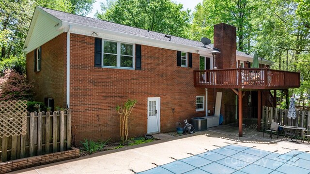 back of house with a wooden deck, brick siding, a patio, and fence