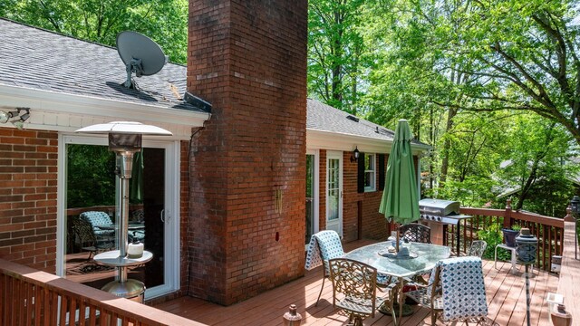 wooden deck with outdoor dining space and a grill