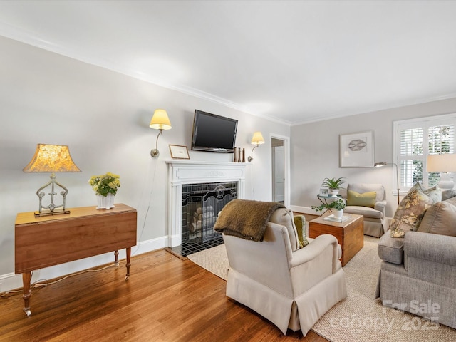 living room with a tile fireplace, wood finished floors, crown molding, and baseboards
