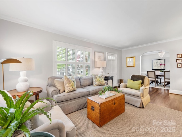 living room with crown molding, arched walkways, wood finished floors, and baseboards