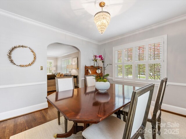 dining room with baseboards, arched walkways, wood finished floors, and plenty of natural light