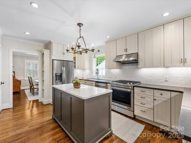 kitchen featuring an inviting chandelier, stainless steel appliances, backsplash, and under cabinet range hood