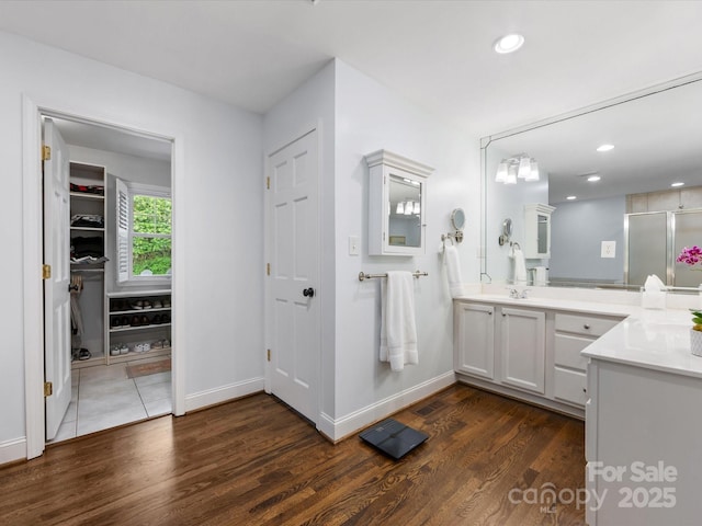 bathroom with baseboards, recessed lighting, wood finished floors, and vanity