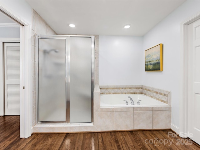 bathroom with recessed lighting, wood finished floors, a shower stall, a closet, and a garden tub