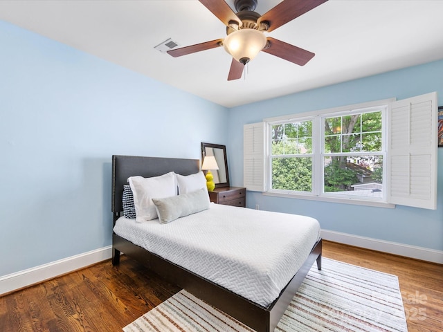 bedroom featuring wood finished floors, visible vents, a ceiling fan, and baseboards