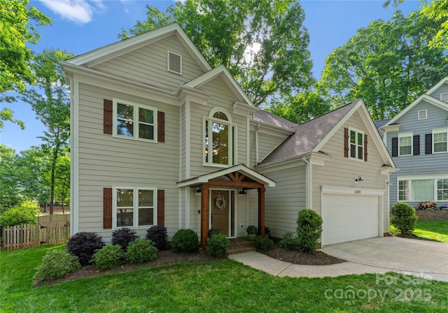 traditional home featuring concrete driveway, an attached garage, fence, and a front yard