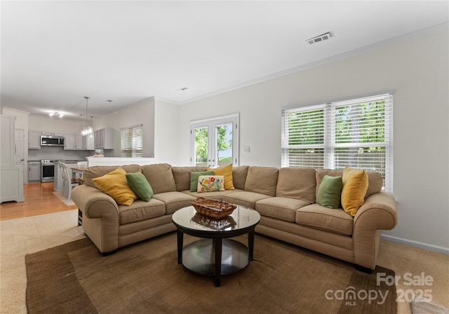 living area featuring visible vents, light carpet, baseboards, and ornamental molding