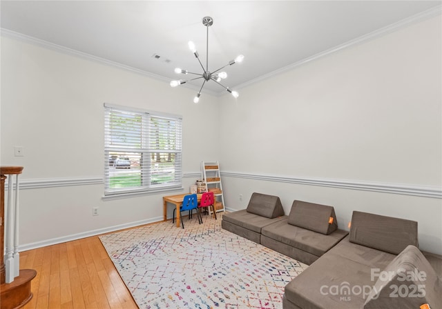 living area with an inviting chandelier, wood-type flooring, baseboards, ornamental molding, and visible vents