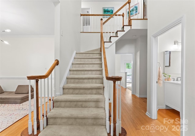 staircase with baseboards, wood finished floors, and crown molding