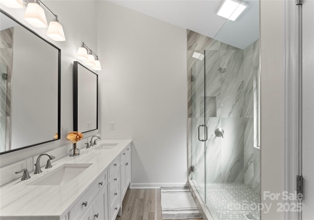 bathroom with a sink, a marble finish shower, and double vanity