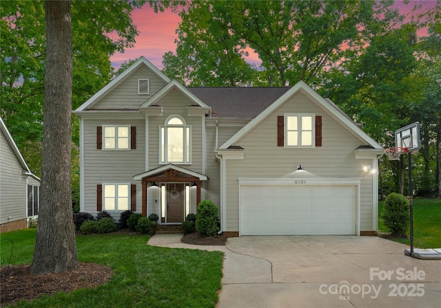 traditional-style house featuring a garage, a yard, and concrete driveway