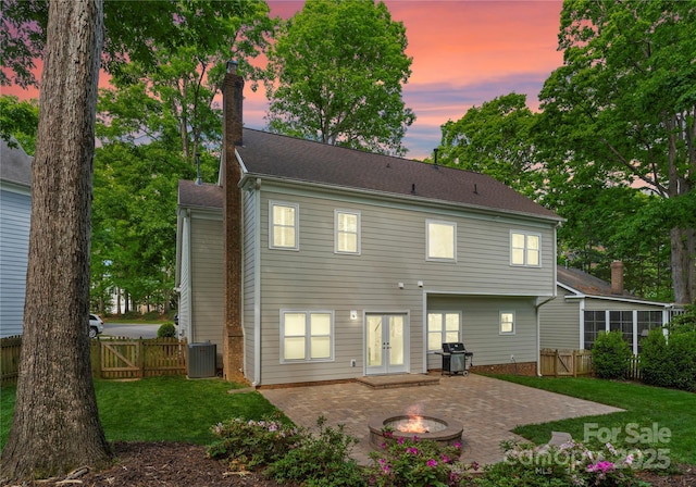 rear view of house with fence, a yard, a patio area, french doors, and an outdoor fire pit