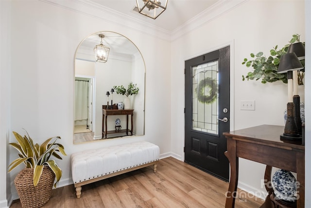 entrance foyer with baseboards, wood finished floors, a notable chandelier, and crown molding