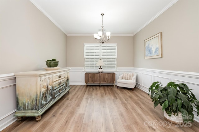 living area with light wood finished floors, ornamental molding, a decorative wall, wainscoting, and a chandelier