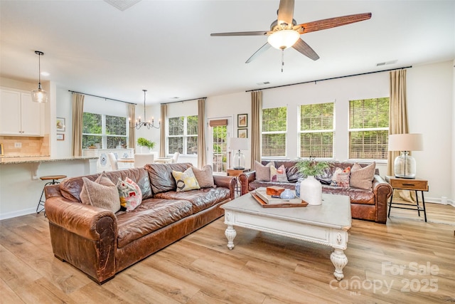 living room with plenty of natural light, visible vents, light wood finished floors, and ceiling fan with notable chandelier