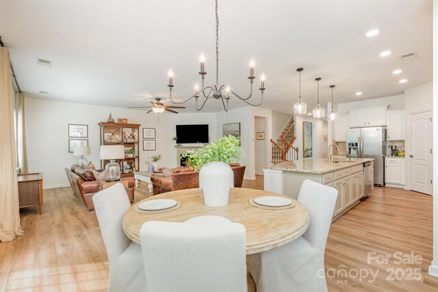 dining room with recessed lighting, stairway, light wood finished floors, visible vents, and ceiling fan with notable chandelier