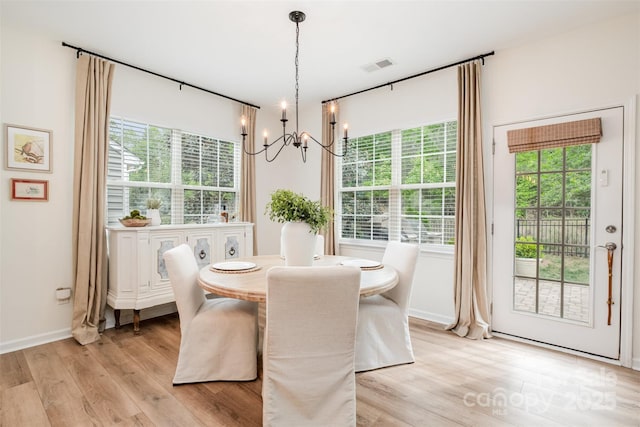 dining room with an inviting chandelier, light wood-style floors, visible vents, and baseboards
