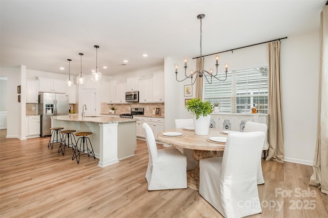 dining space with recessed lighting, light wood-style flooring, and a notable chandelier