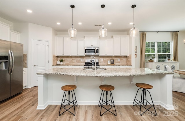 kitchen with tasteful backsplash, light wood finished floors, stainless steel appliances, and a sink